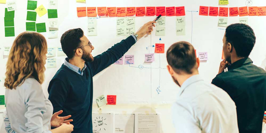 Gruppe Studierender vor einem Whiteboard mit farbigen Post-Its