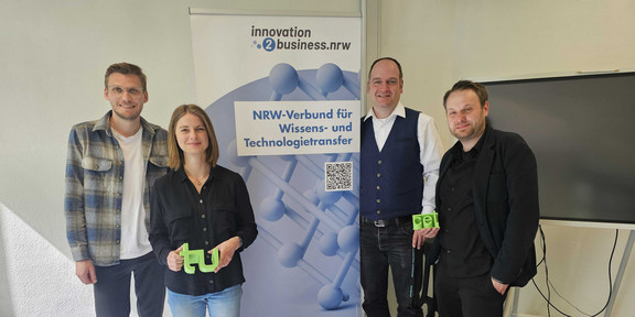 4 Personen vor einem Banner