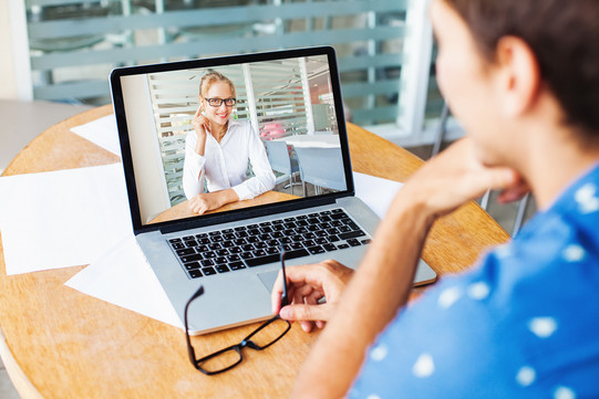 Frau sitzt und hält eine Videokonferenz auf ihrem Laptop mit einer anderen Frau ab