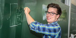 student_an_tafel Ein Student schreibt eine mathematische Gleichung an eine Tafel